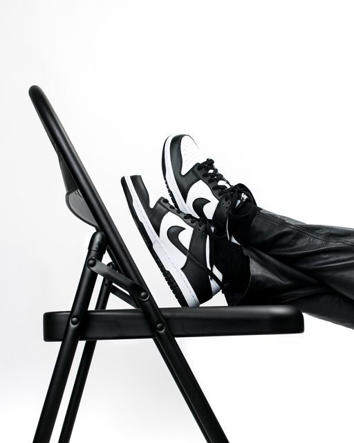 Stylish black and white Nike Dunk sneaker displayed on a chair, representing the ForeverDrip Nike collection.