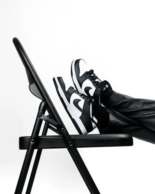 Stylish black and white Nike Dunk sneaker displayed on a chair, representing the ForeverDrip Nike collection.