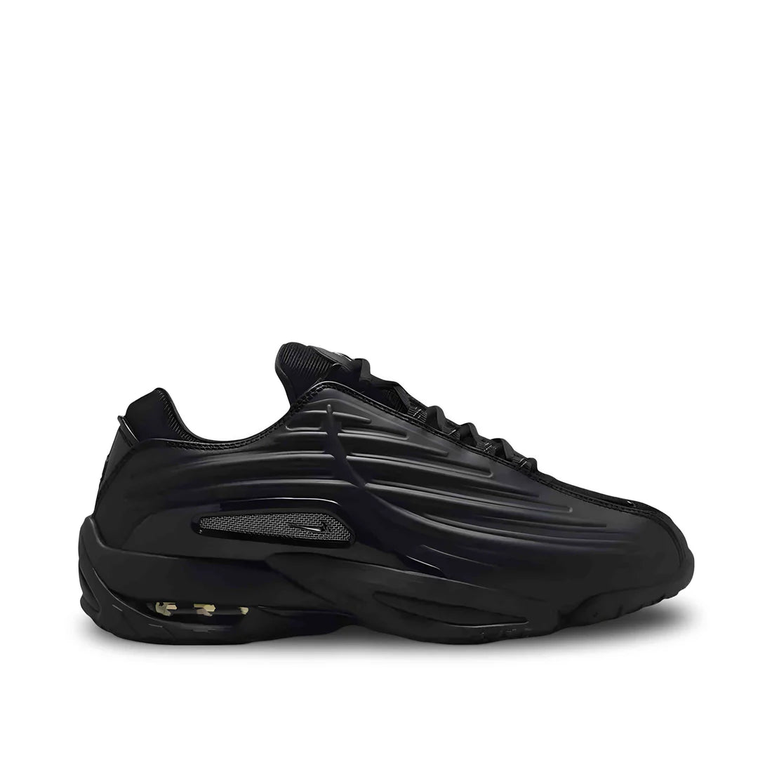 Side view of Nike NOCTA Hot Step 2 in Black Gunmetal, showing textured upper, air-cushioned midsole, and NOCTA branding.